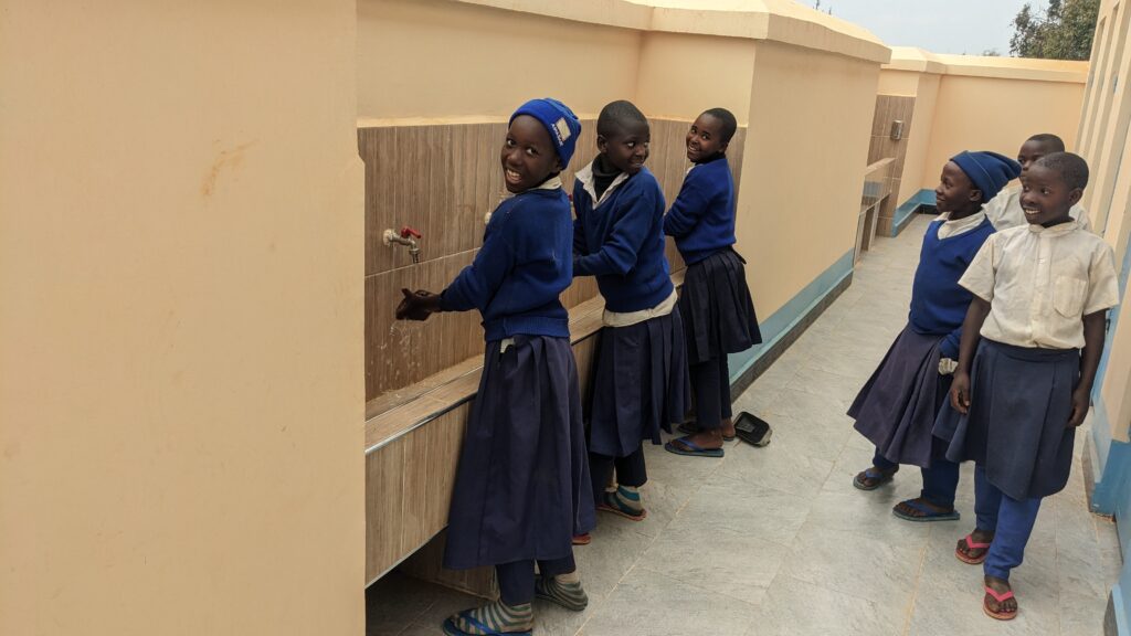 Schulkinder in blauer Schuluniform waschen sich die Hände.