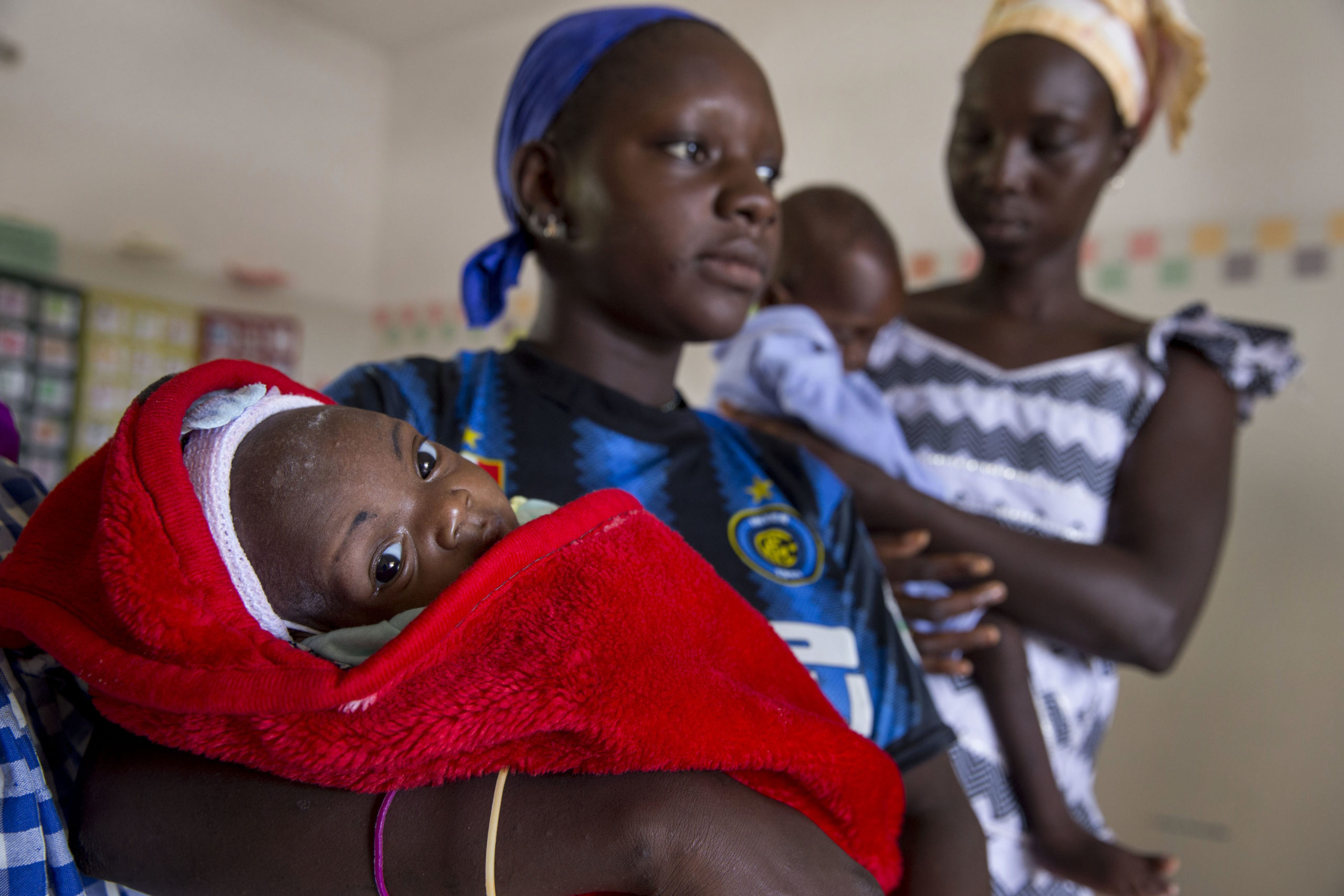 Mütter halten in ihren Armen ihre Kinder in Decken gewickelt in einem Krankenhaus im Senegal.