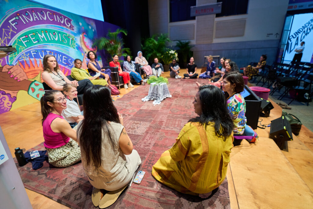 Teilnehmer*innen sitzen im Kreis und reden über Entwicklungsfinanzierung in unterschiedlichen Kontexten.