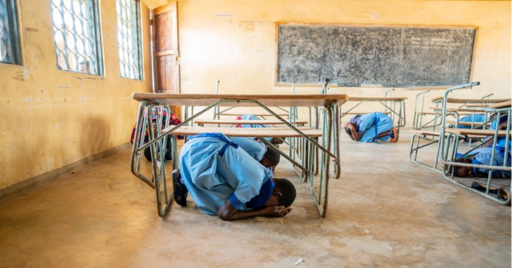 Schüler*innen in Malawi suchen Schutz unter den Tischen bei einer Sicherheitsübung.
