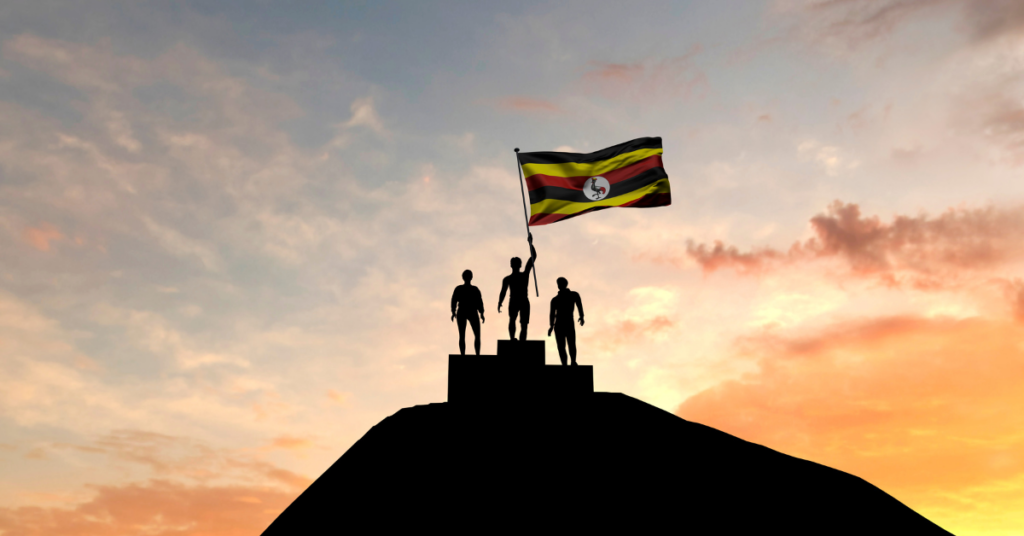 Menschen strecken die Flagge von Uganda hoch vor der untergehenden Sonne.
